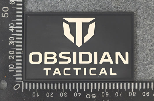 Obsidian Tactical logo patch on a textured surface with a ruler for scale.